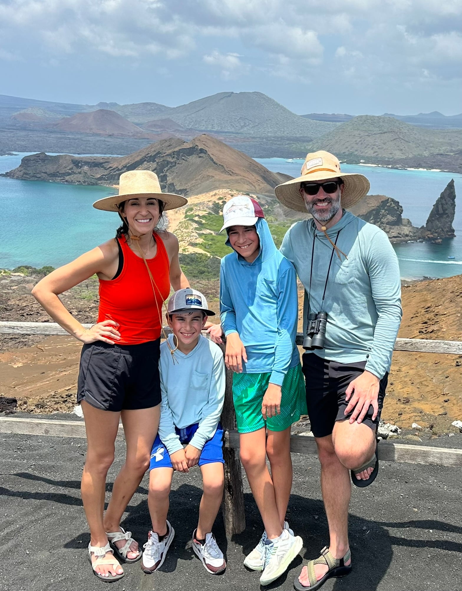 Family on volcanic rock overlooking turquoise water in the Galápagos